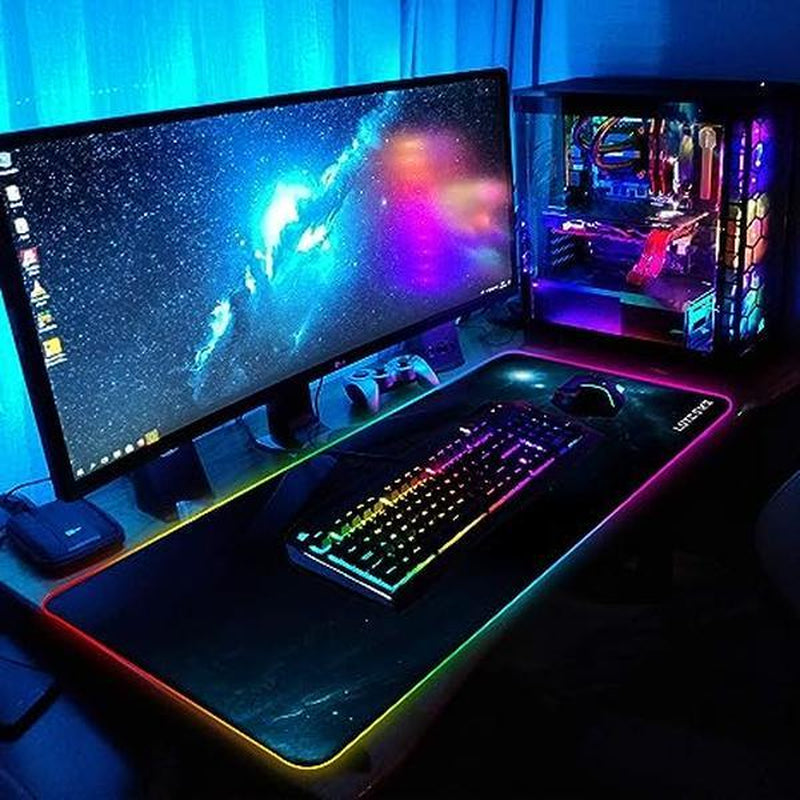 Gaming setup with a large monitor, keyboard, and RGB lighting on a desk.
